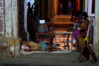En la puerta de su casa duerme un hombre mientras otros pasan el tiempo tratando de refrescarse en la calle en La Habana, Cuba, (Infobae Centroamérica/AP Foto/Ramón Espinosa)