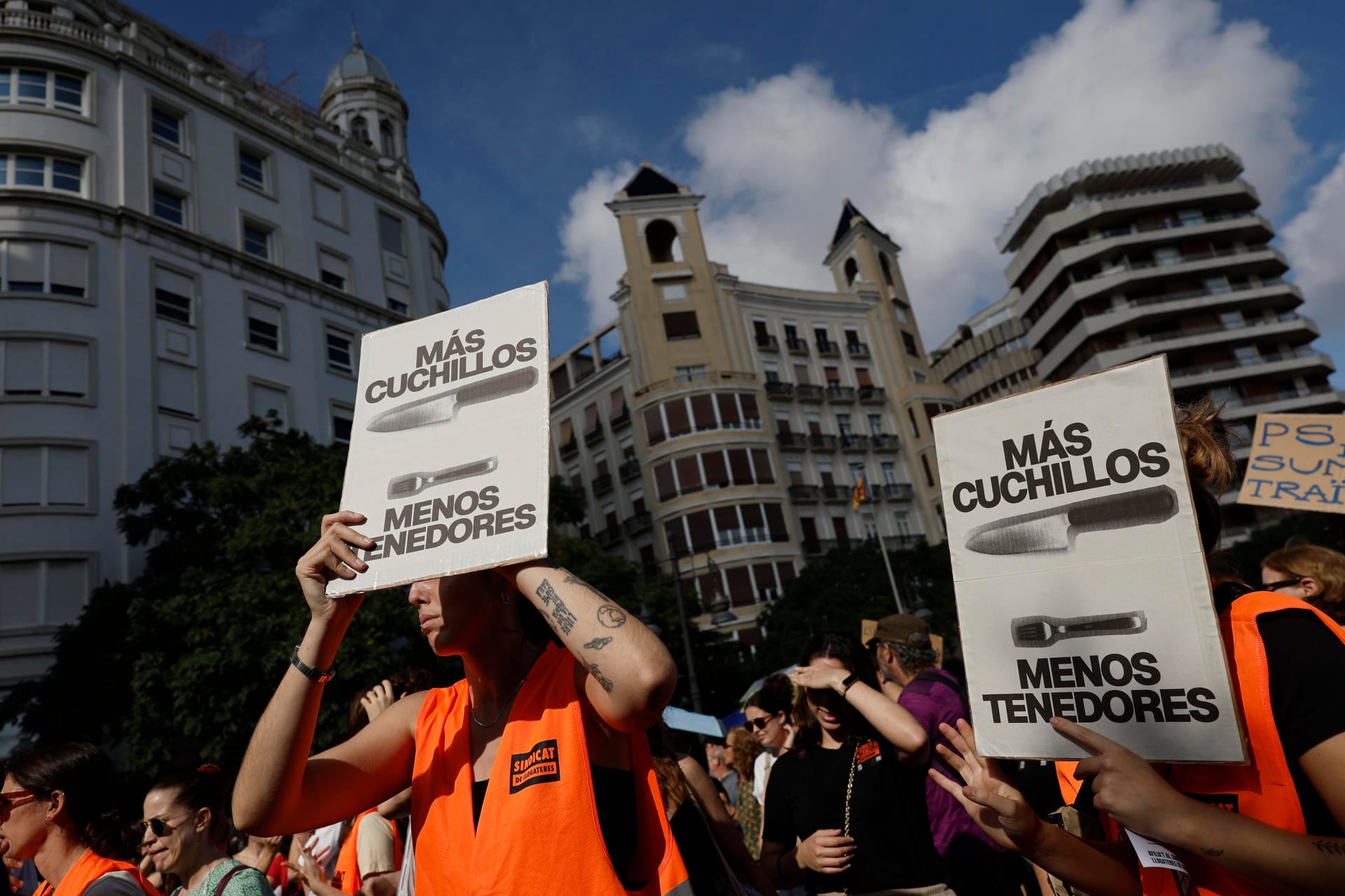 Varias personas con chalecos naranjas del Sindicat de Llogateres sostienen pancartas reivindicativas durante una manifestación en la vía pública.