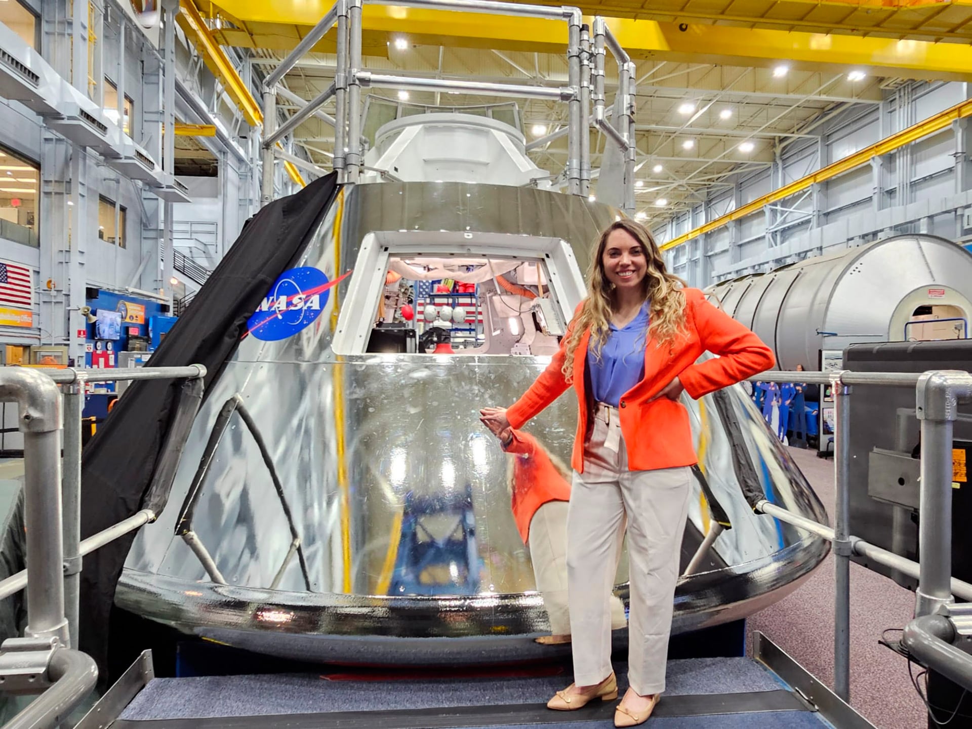 Lorna Evans de NASA sonríe junto a la cápsula espacial Orion en una instalación de la agencia, donde se prepara para futuras misiones espaciales