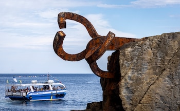 Un barco turístico pasa este lunes junto a la escultura el Peine del Viento, de Eduardo Chillida, en San Sebastián. (EFE/Javier Etxezarreta)