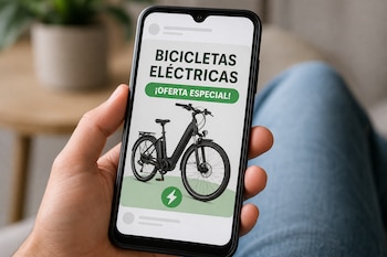 Una mano sostiene un teléfono celular cuya pantalla muestra un anuncio publicitario con la imagen de una bicicleta eléctrica negra.