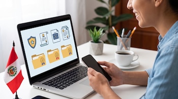 Una persona sonríe mientras usa una laptop y un teléfono móvil en un escritorio; la pantalla de la laptop muestra iconos de documentos y carpetas, junto a una bandera de Perú.