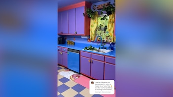 Una cocina de diseño colorido con gabinetes morados, encimeras azules, un lavaplatos azul y un fregadero blanco. Cortinas amarillas con maíz en la ventana