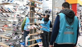 Dos efectivos de la Policía de la Ciudad inspeccionan estantes llenos de zapatillas en un local comercial, en el marco de un operativo
