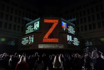 Retratos de soldados rusos caídos en Ucrania y el símbolo "Z" proyectados sobre el edificio del Consejo de Estado en Simferopol, Crimea ocupada, en abril de 2024. Para Pankieiev, el Kremlin ya no logra sostener una narrativa coherente puertas adentro. (REUTERS/Alexey Pavlishak)