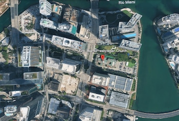 Vista aérea de un área urbana con edificios, calles, un río, un puente y vegetación. Se distingue la First Miami Presbyterian Church con un marcador rojo