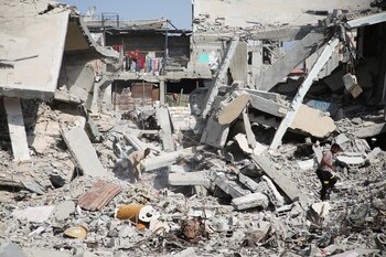 Palestinos caminan sobre escombros de