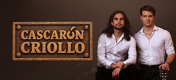 Dos hombres con camisa blanca posan junto a un letrero de madera con el texto Cascarón Criollo sobre un fondo marrón