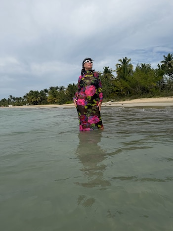 Moria Casán posó dentro del agua con un vestido largo de red transparente con estampado de flores fucsia y rojas, descalza y con anteojos blancos
