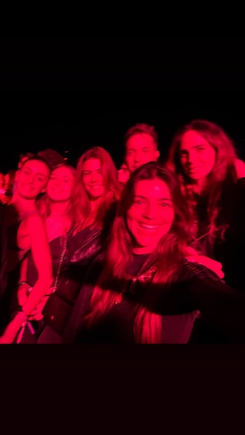 Un grupo de personas posa para un autorretrato en un espacio oscuro iluminado por una luz de color rojo