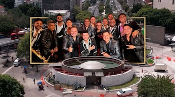 Fotografía de trece hombres sonrientes con sacos oscuros dentro de un marco dorado, superpuesta sobre una vista aérea de una plaza urbana.