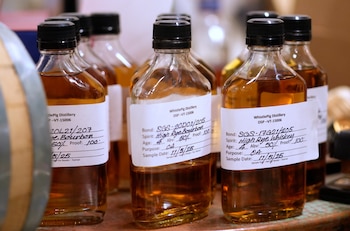 Primer plano de varias botellas de cristal pequeñas con tapones negros y etiquetas blancas, conteniendo líquido ámbar oscuro. Las etiquetas tienen texto manuscrito