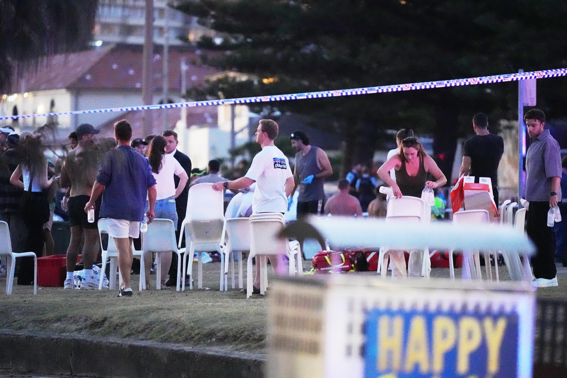 La gente y los trabajadores de emergencia se reúnen en el lugar donde se estaba llevando a cabo un evento festivo y luego se informó de un tiroteo en Bondi Beach.