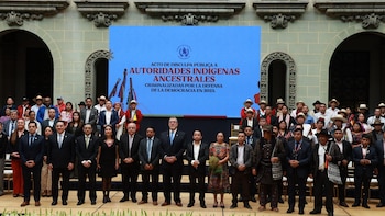 Un grupo de funcionarios y autoridades indígenas posan frente a una pantalla azul durante un acto oficial en Guatemala