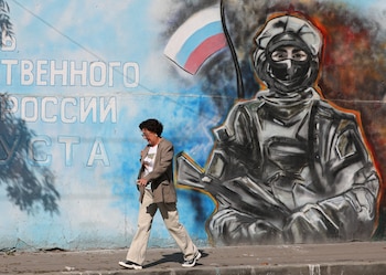 Una mujer pasa caminando frente a un mural que representa a un soldado con la bandera rusa en Crimea. (REUTERS/Alexey Pavlishak)