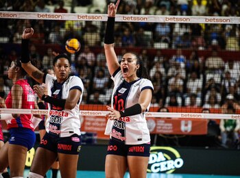 Maeva Orlé, con uniforme de Alianza Lima, grita y alza el brazo derecho en celebración junto a una compañera en un partido de voleibol