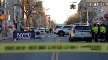 Una cinta policial amarilla cruza una calle cortada con patrullas de la policía de Nueva York y varios agentes en la escena