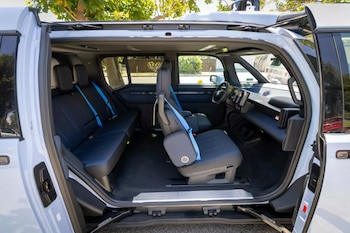 Interior de un vehículo utilitario deportivo compacto con puertas delanteras y traseras abiertas, mostrando asientos oscuros con cinturones de seguridad azules y el panel de instrumentos