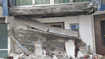 Fachada de un edificio colapsada con escombros de concreto y ladrillos en el suelo, exponiendo la estructura interna bajo una ventana