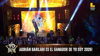 Un cantante en un escenario iluminado frente al público, con una pantalla dorada de fondo y un rótulo que anuncia al ganador