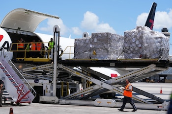 Personas cargan pales con alimentos y kits de higiene en un avión con destino a Cuba organizado por el gobierno de Estados Unidos. (AP Foto/Lynne Sladky)