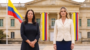 Pilar Rueda y Ana Lucía Pineda de pie frente a la Casa de Nariño, con la bandera de Colombia. Pilar lleva vestido oscuro, Ana Lucía blazer crema.