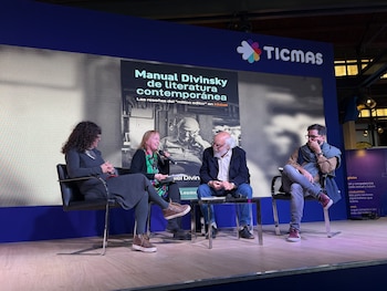 Cuatro personas sentadas en un escenario con piso de madera. Detrás, una pantalla muestra "Manual Divinsky de literatura contemporánea" y un logo de TICMAS. Una mujer sostiene un micrófono