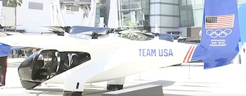 Aeronave de taxi aéreo blanca y azul con la bandera de Estados Unidos, los anillos olímpicos y la inscripción Team USA