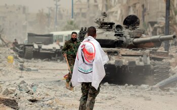 Un soldado del Ejército sirio porta una bandera de la Fuerza de la Defensa Nacional Siria (FDN) . EFE/Youssef Badawi/Archivo