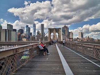 Visitantes descansan y recorren el puente con el skyline del Bajo Manhattan de fondo. La presión inmobiliaria y la densidad urbana han impulsado proyectos que buscan maximizar el uso del espacio en zonas clave como este corredor.