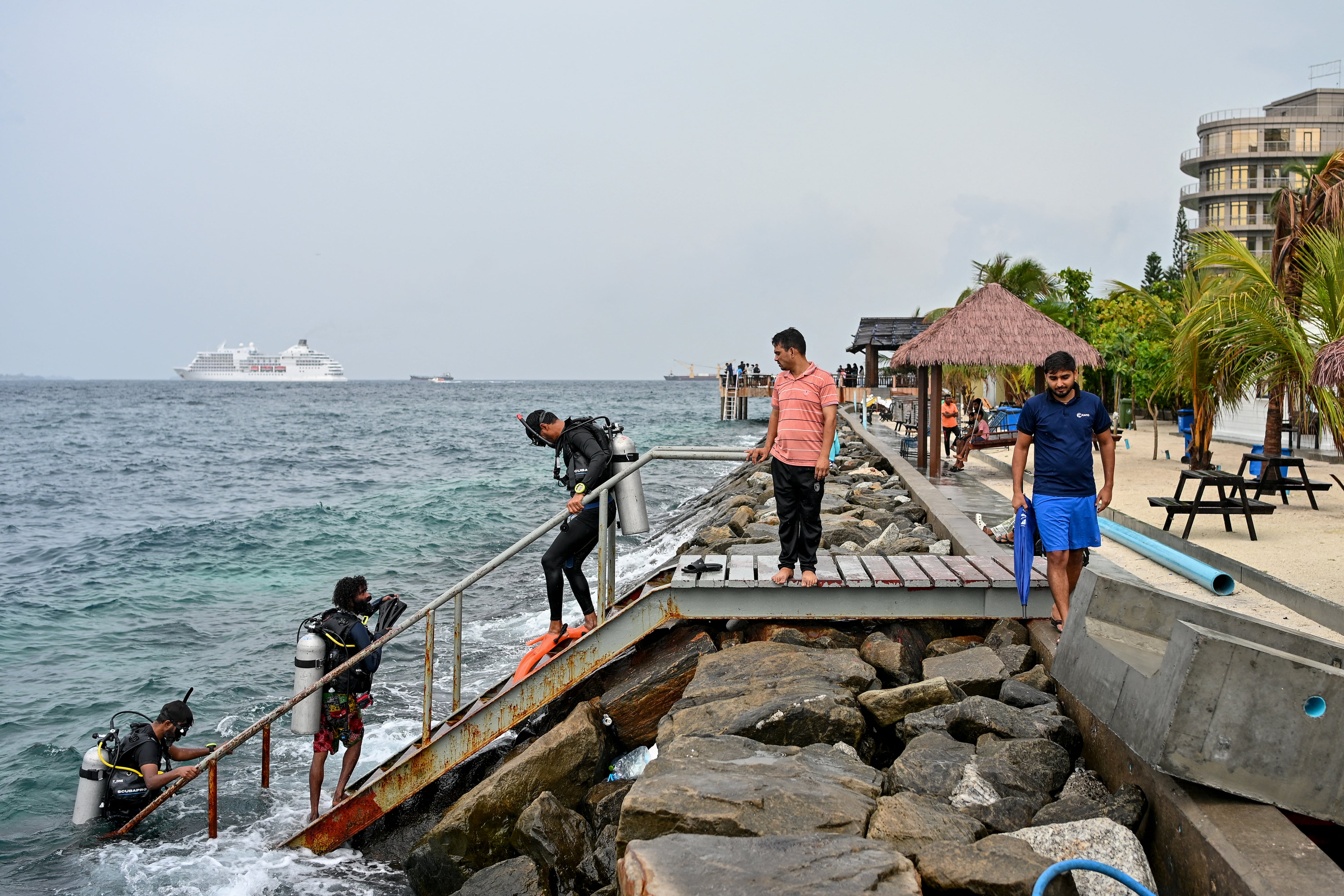 Un turista, acompañado de guías, regresa tras una sesión de buceo en aguas abiertas cerca de la playa de Rasfannu en Malé el 15 de mayo de 2026. Equipos de rescate en el archipiélago de las Maldivas, en el océano Índico, buscaron por segundo día consecutivo, el 15 de mayo, los cuerpos de cuatro italianos desaparecidos tras el accidente de buceo más mortífero en la historia del país, según informaron las autoridades (Foto de Mohamed Afrah/AFP)