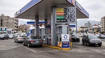 Estación de servicio Primax con tablero electrónico de precios de combustible, surtidores, automóviles y un letrero de Osinergmin.