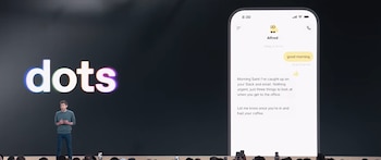 Un hombre en un escenario junto a una pantalla con el texto dots y la imagen de una aplicación de mensajería en un teléfono