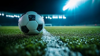 Balón de fútbol en cancha, césped vibrante, estadio iluminado, juego en marcha, textura realista, ambiente deportivo, pasión futbolera, fútbol profesional, deporte emocionante, preparación para el partido. - (Imagen Ilustrativa Infobae)