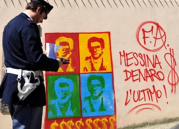 Un policía observa un grafiti con la imagen de Matteo Messina Denaro en Palermo, en 2008. Italia incautó ahora 200 millones de euros de su fortuna. (AP Foto/Alessandro Fucarini, archivo)