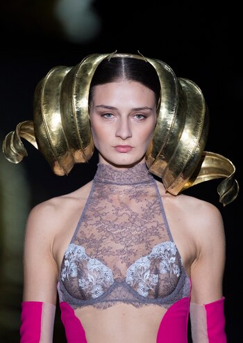 Andrés Sardá presentó un brasier de encaje de cuello halter y aro. ¿Lo extravagante? El estilismo del look. Un casquete dorado de orejas onduladas y guantes y corsé fucsias
