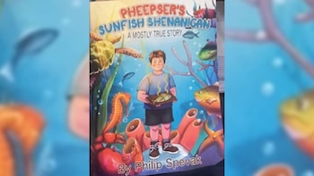 La portada de un cómic muestra a un niño bajo el agua, rodeado de tortugas, caballitos de mar y peces, sosteniendo un pescado cocinado