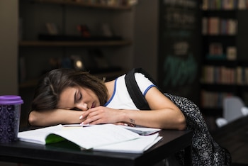 Una chica se queda dormida estudiando en la biblioteca (Magnific)