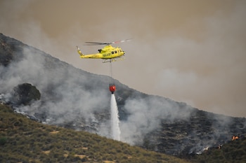 Un helicóptero del servicio de extinción de incendios arroja este viernes agua sobre uno de los focos del incendio forestal declarado en Los Gallardos, Almería. (Carlos Barba/EFE)