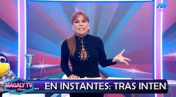 Magaly Medina en estudio de televisión con un muñeco de pingüino, una copa y logos de "Magaly TV La Firme" y "ATV vivo"
