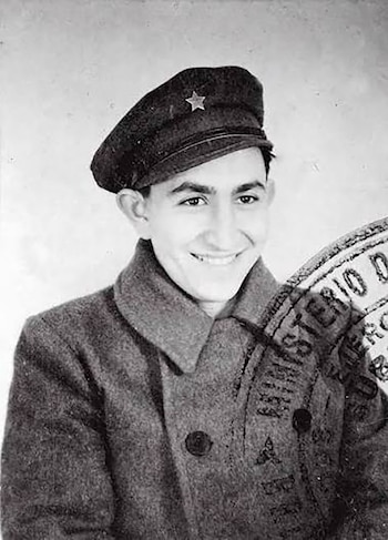 Fotografía en blanco y negro de un hombre joven con gorra militar de estrella, abrigo y un sello oficial impreso