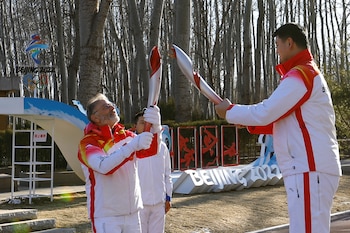 Olympics - Beijing 2022 Winter Olympics - Torch Relay - Beijing, China - February 2, 2022. President of Chinese Basketball Association and Ice and Snow Sports Promotion Ambassador Yao Ming passes on the Olympic flame to Greek Ambassador to China Georgios Iliopoulos at the Olympic Forest Park. REUTERS/Yew Lun Tian