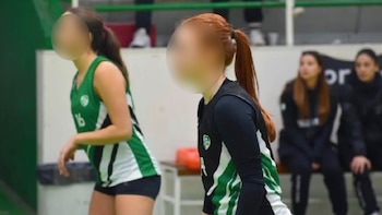 Dos jugadoras de voleibol de pie en una cancha, una con camiseta verde y número 16, la otra con camiseta negra, verde y blanca