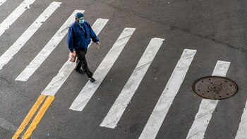 Un transeúnte con cubrebocas cruza