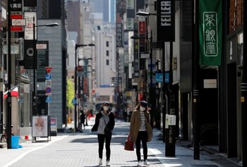 FOTO DE ARCHIVO: Dos mujeres con mascarillas pasean por la calle de un distrito comercial desierto durante el brote de la enfermedad del nuevo coronavirus (COVID-19) en Tokio, Japón, el 25 de abril de 2020. REUTERS/Kim Kyung-Hoon