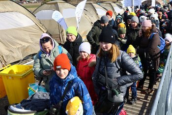 Personas y niños esperan cerca de tiendas de campaña después de cruzar la frontera de Ucrania a Polonia, tras huir de la invasión rusa de Ucrania, en el puesto de control fronterizo de Medyka, Polonia, 10 de marzo de 2022. REUTERS/Fabrizio Bensch