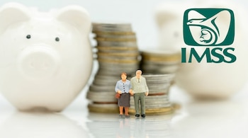 Una pareja de figuras de adultos mayores frente a pilas de monedas y dos alcancías de cerdito blancas, con el logotipo de IMSS al fondo.