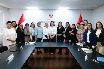 Grupo de catorce mujeres posan sonrientes en una oficina. Keiko Fujimori está al centro. Detrás hay una pared blanca con el escudo peruano y dos banderas de Perú. Una mesa oscura en U ocupa el primer plano