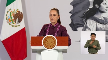 Claudia Sheinbaum ante un podio con el escudo nacional, la bandera de México y un recuadro con un intérprete de lengua de señas.