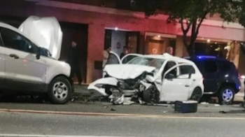 Un automóvil blanco con la parte frontal destruida junto a otros vehículos dañados en una calle de noche